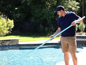 Maintenance worker vacuuming inground pool